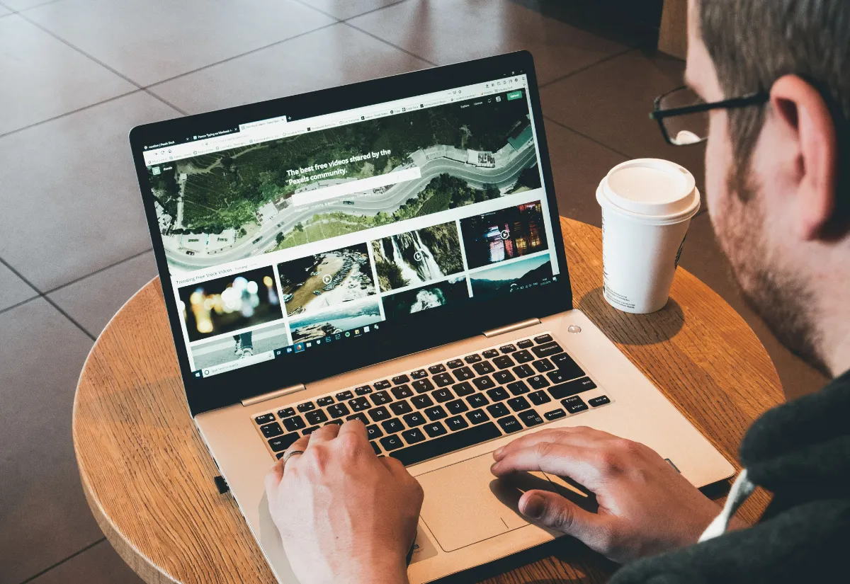 A person browsing a photo-sharing website on a laptop while working from a café table.